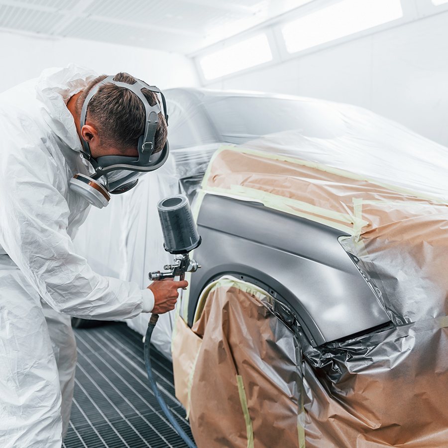 Technician spraying a fender in the paint booth